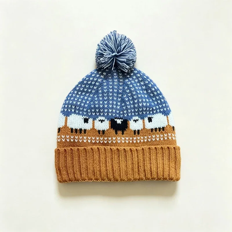 Blue and ochre pom pom beanie with a knitted sheep motif