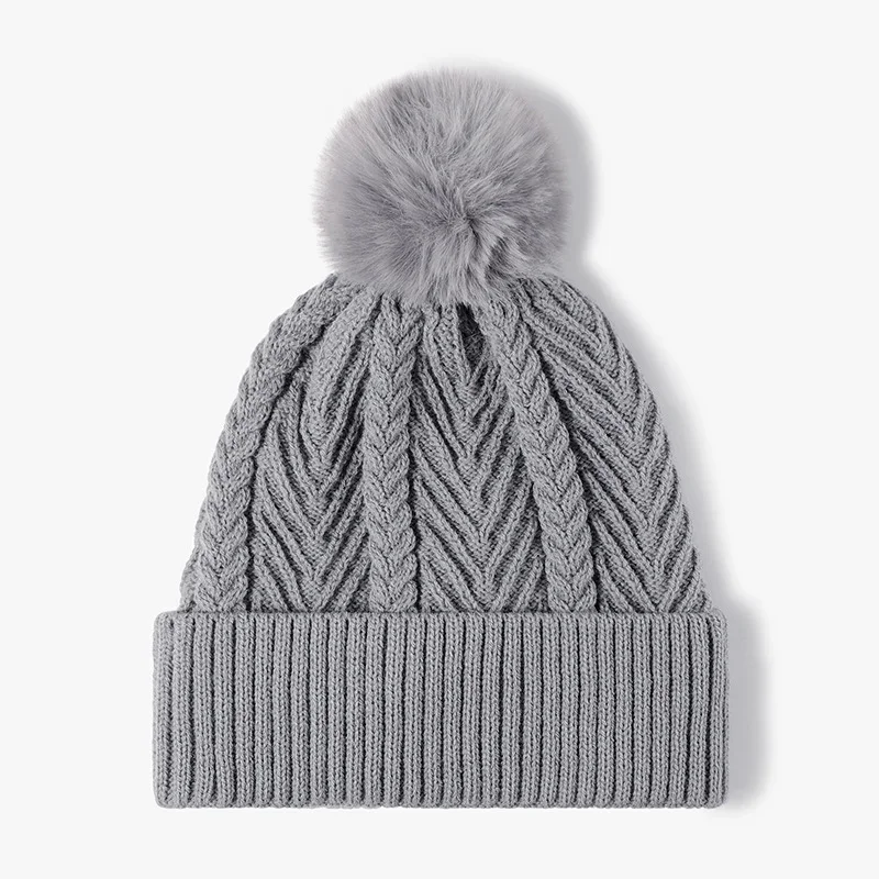 Blue grey cable knit beanie with a folded ribbed cuff and grey pom