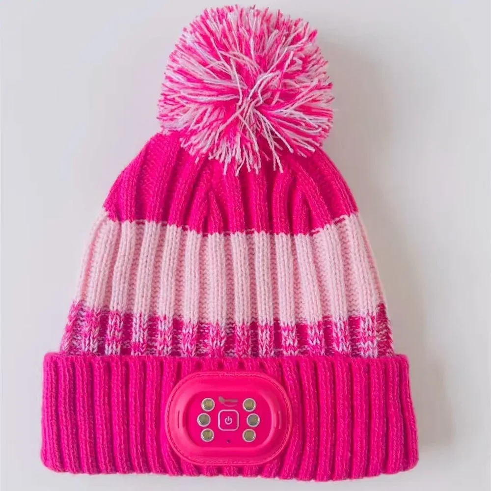 Bright pink pom-pom knit beanie with a small LED lighting module on the folded cuff.