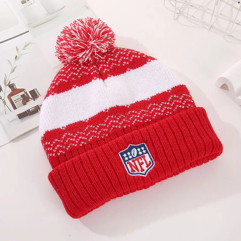 Red and white striped pom pom beanie with an nfl shield patch