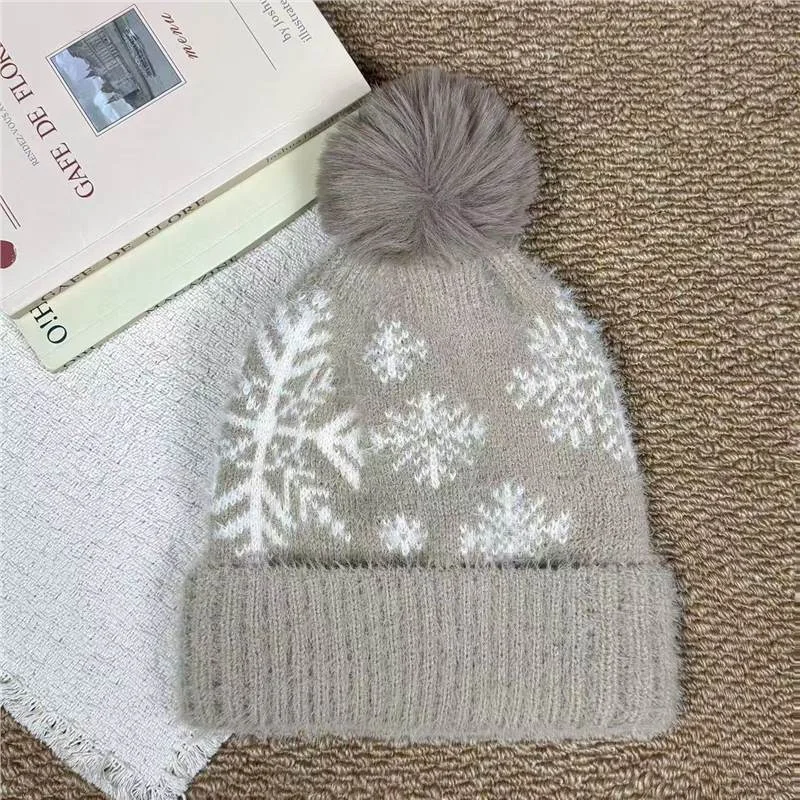 Taupe pom pom beanie with white snowflake motifs and a folded cuff