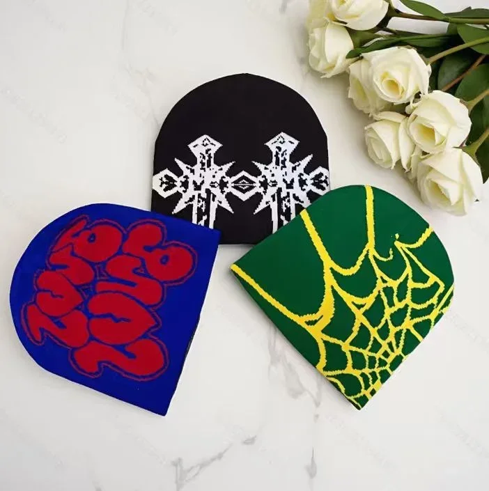 Three knitted beanies in blue, black and green with graphic motifs.